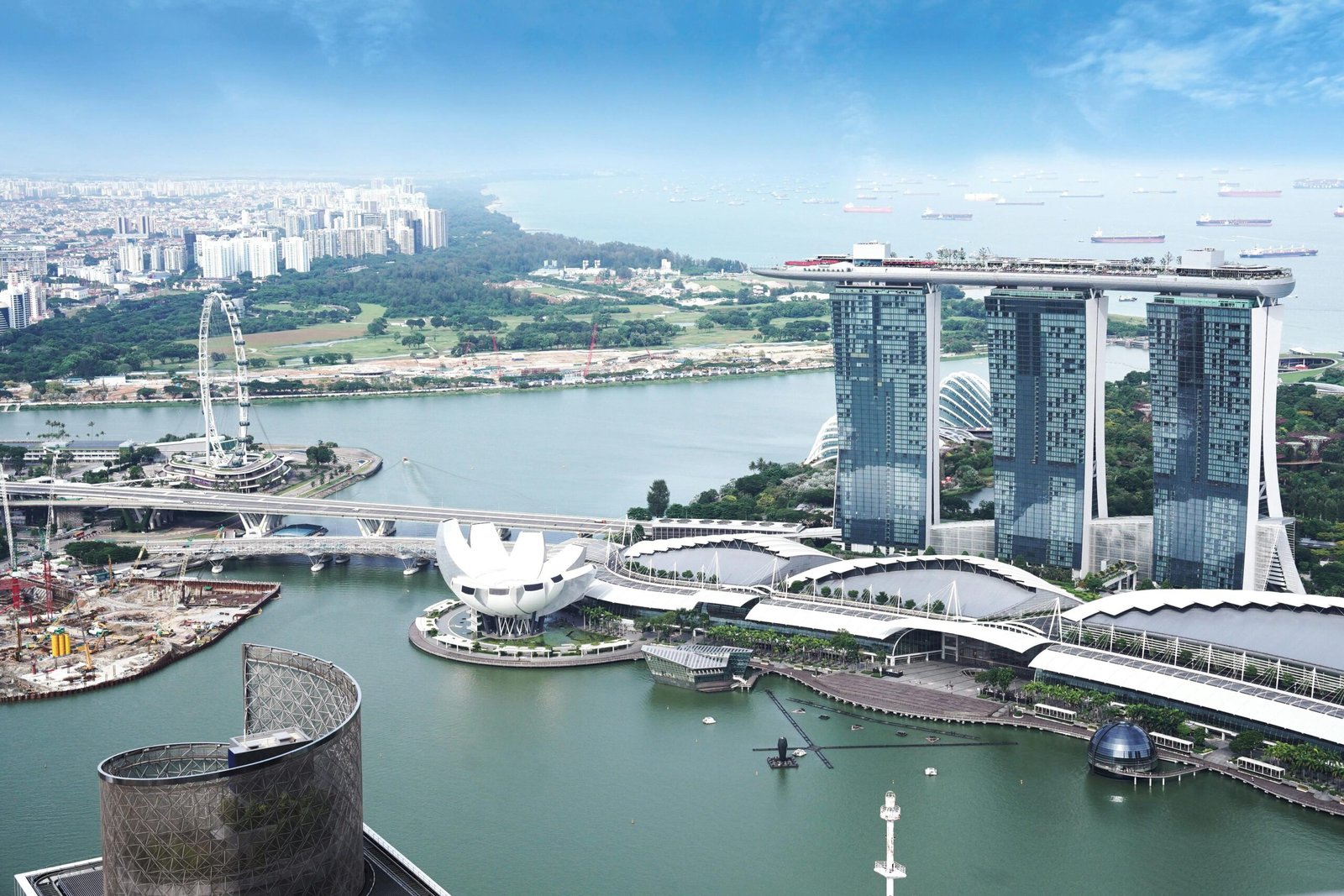 A luxury corporate summit in Singapore 2026, showing executives using a glowing amber holographic networking display on a rooftop terrace overlooking Marina Bay at sunset.